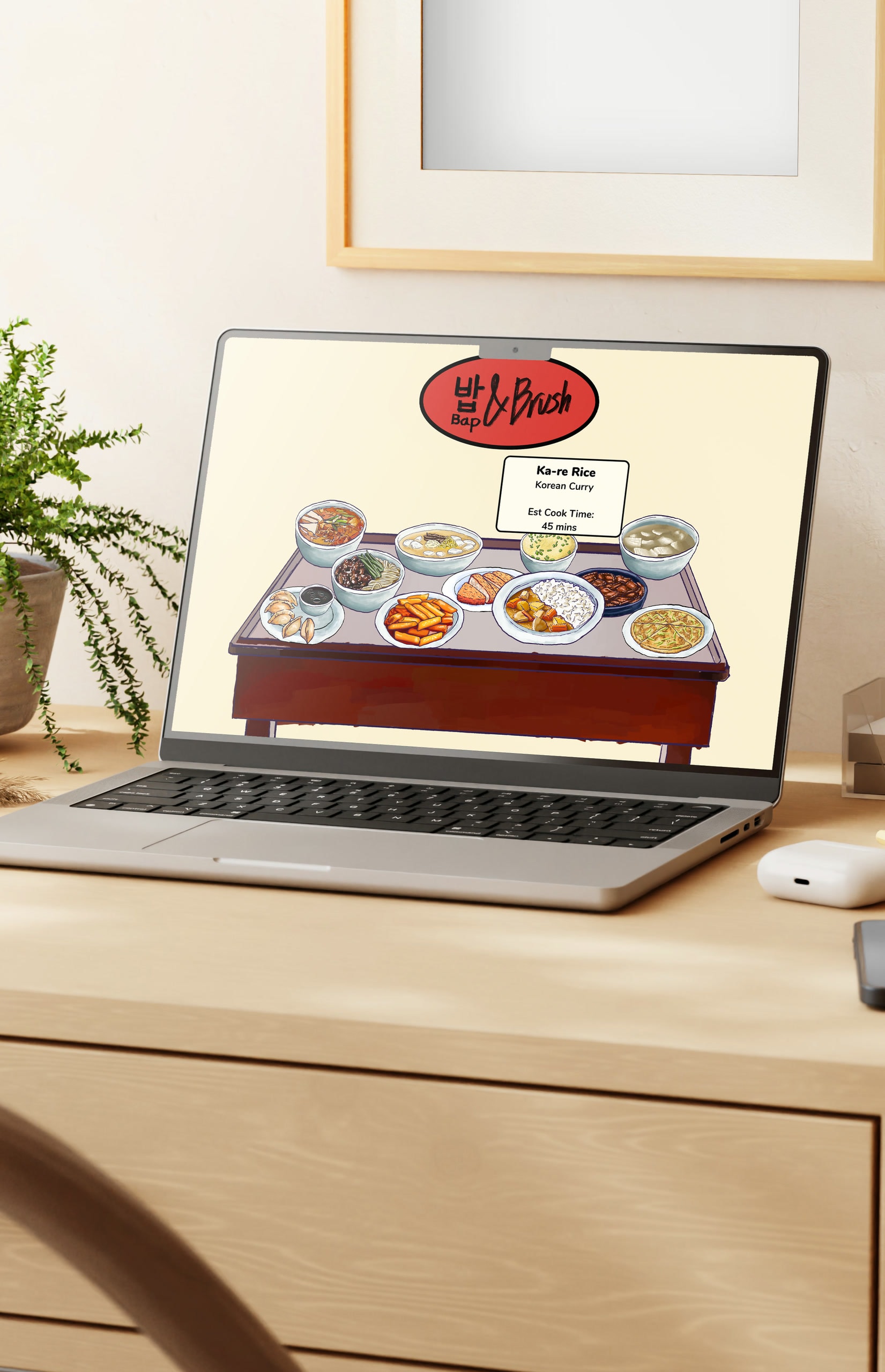 A laptop on a light wood desk showing the Bap & Brush site: the red oval “밥 Bap & Brush” logo above a painted spread of Korean dishes laid across a low table, with a card reading “Ka-re Rice — Korean Curry — Est Cook Time: 45 mins”.